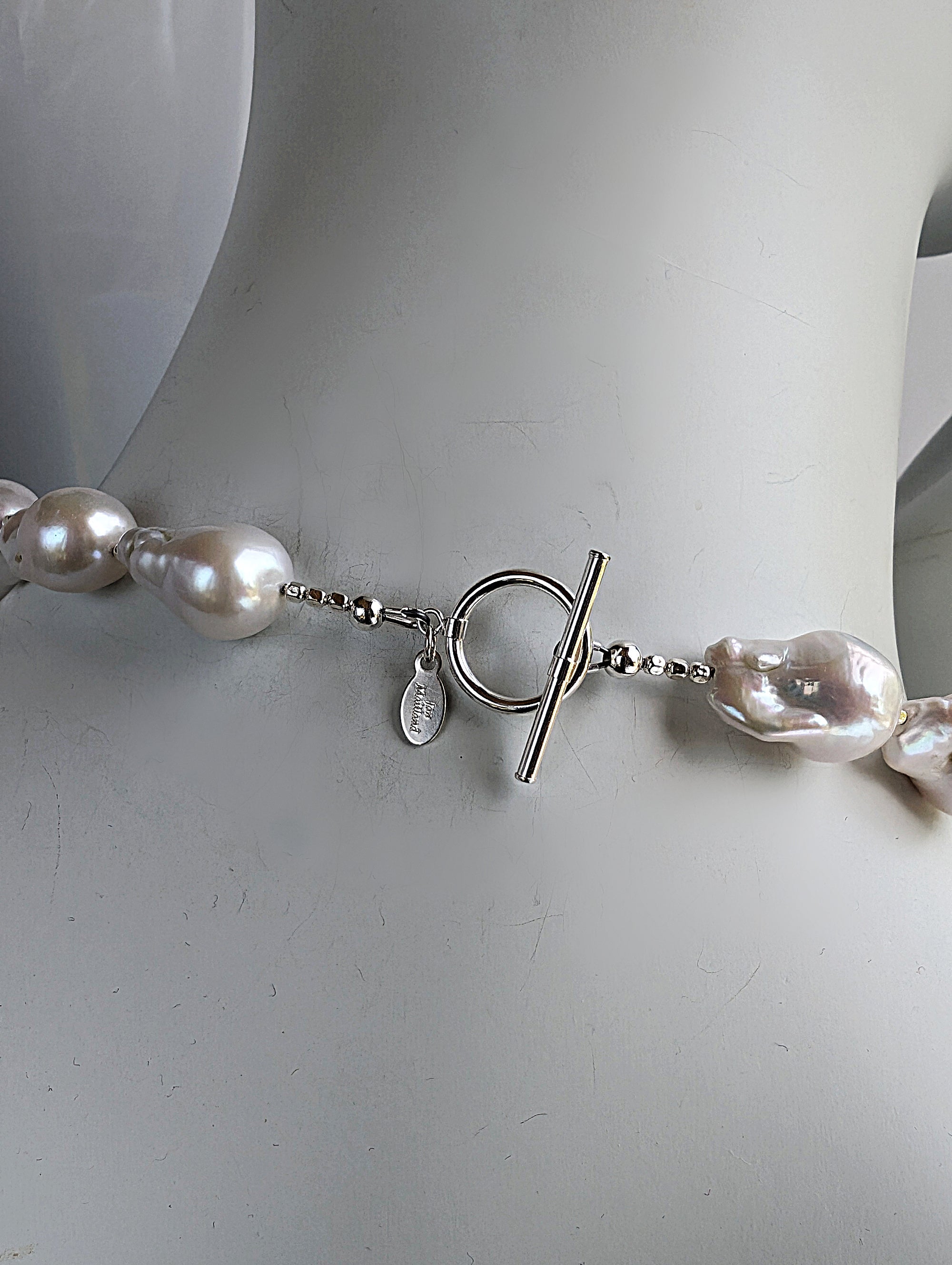Back of White Baroque pearl necklace showing sterling silver toggle clasp and designer signature tag.