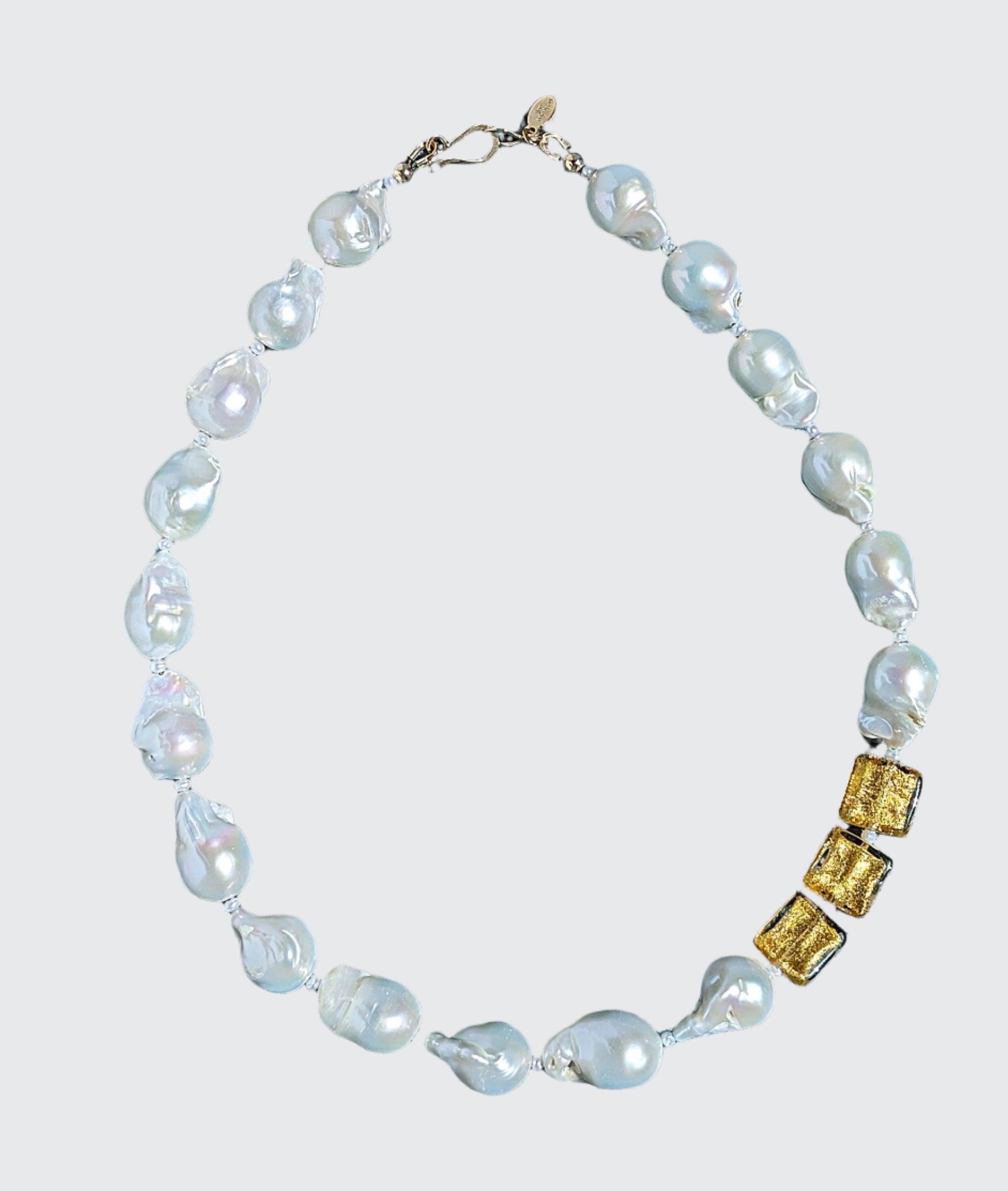 Radiant Baroque Pearls and Gold Necklace -Adorn yourself with the exquisite elegance of luxurious white baroque pearls. Three square 24 Karat gold foil lamp work Venetian glass beads are enhanced in the design, and are to be worn on the left shoulder. Small freshwater pearls are included and reveal themselves between each of the large pearls and gold beads. The piece is secured with a 14 Karat gold hook and eye clasp, showcasing the artist&