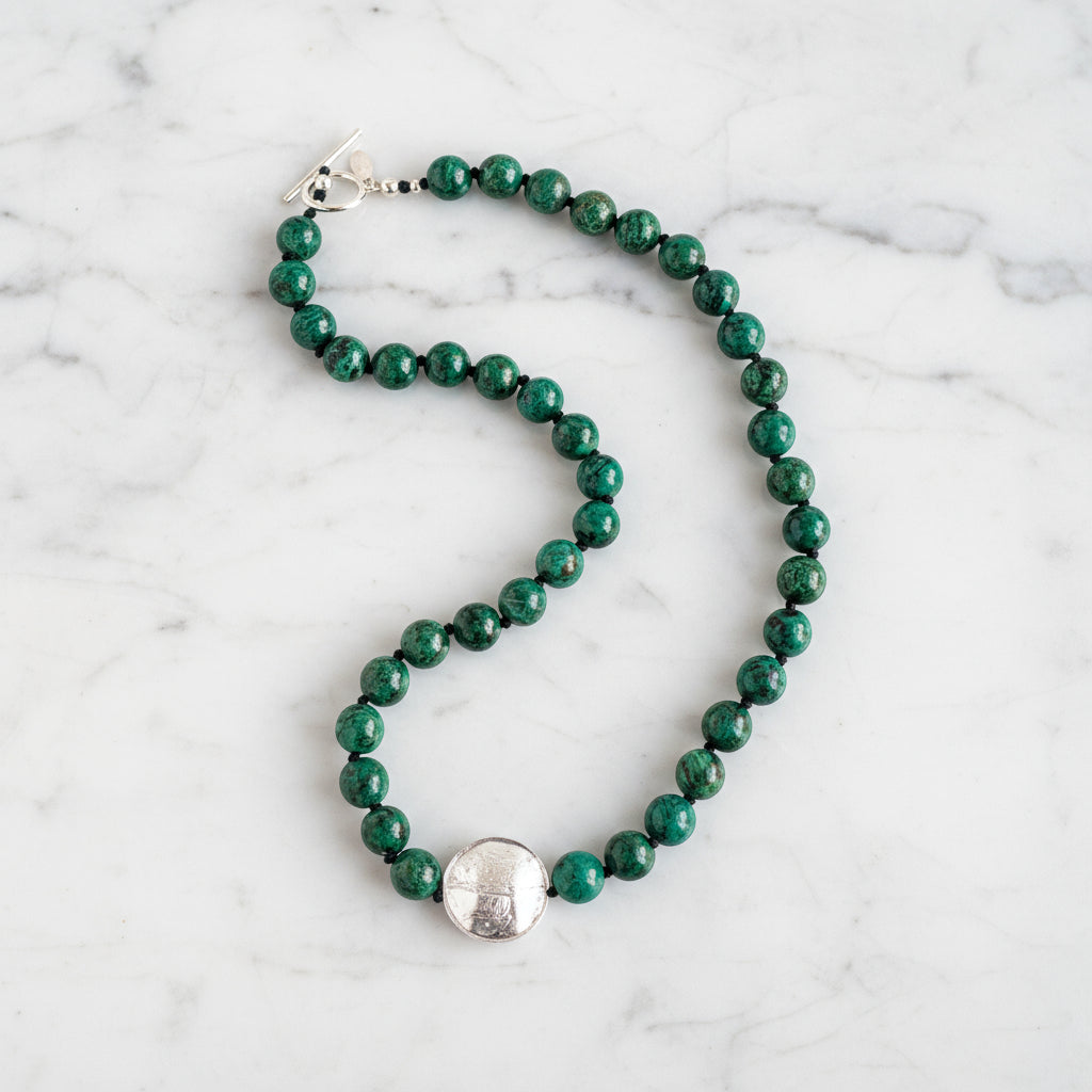An image of a silver toggle clasp on a necklace with hand-knotted chrysocolla beads and lampwork glass.