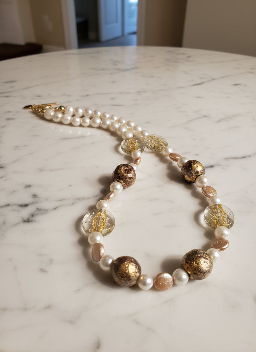Pearl necklace with gold gilded beads, Czech glass beads on a white marble table.
