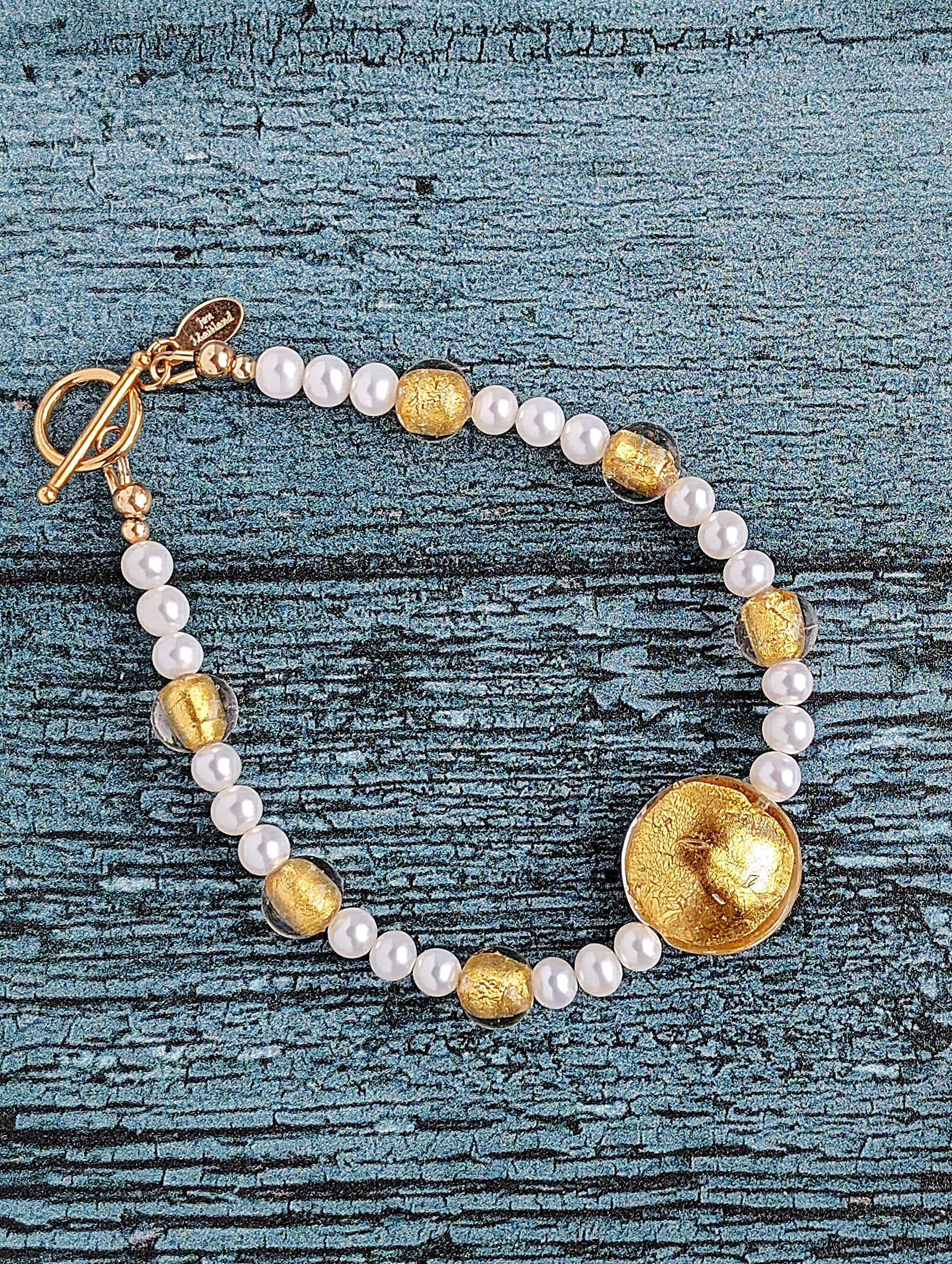 White pearl bracelet with gold Venetian lamp work glass beads, large center bead in 24 karat gold foil lamp work Venetian glass. The bracelet is finished with gold toggle clasp and designer tag.