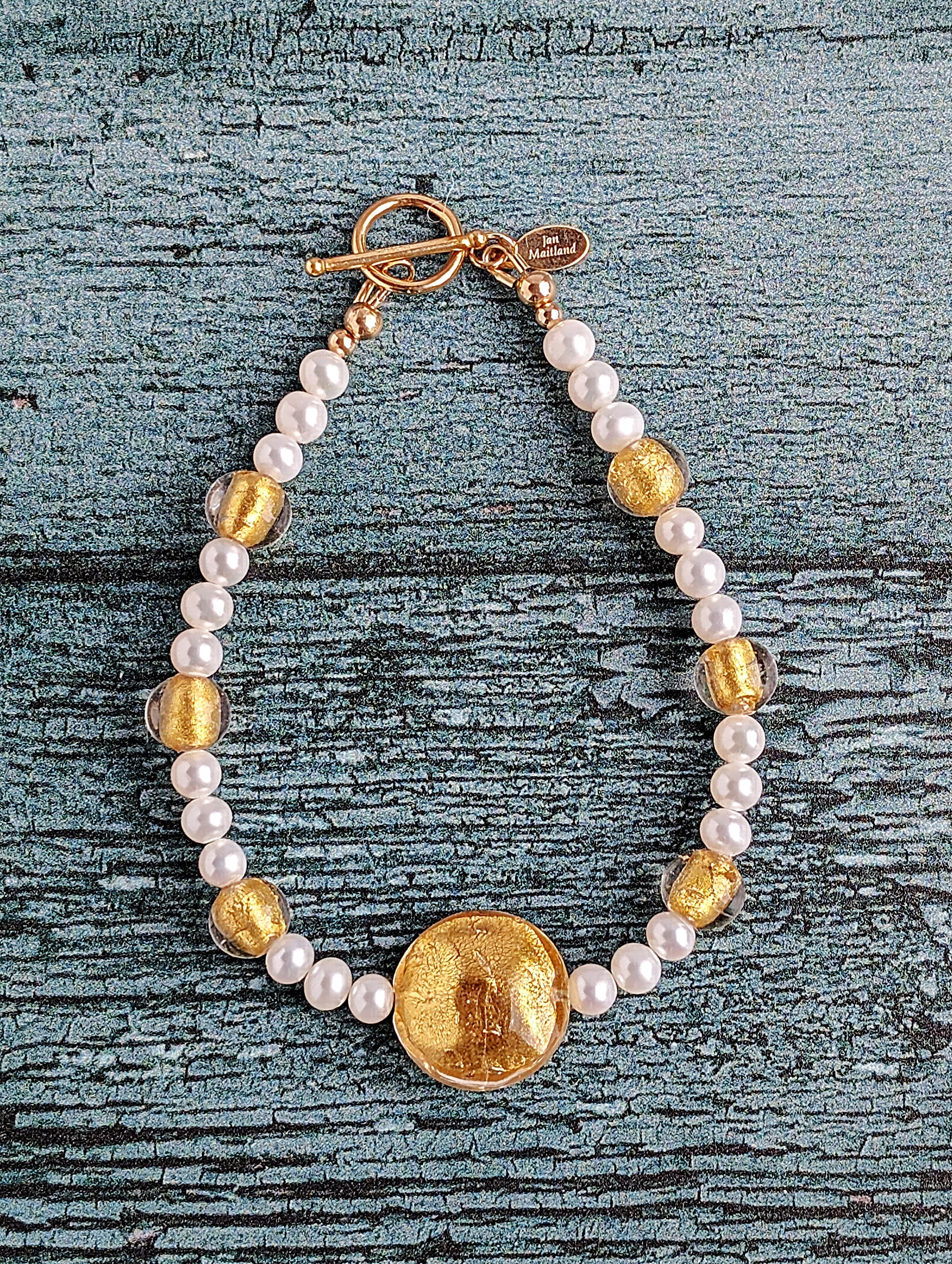 White pearl bracelet with gold Venetian lamp work glass beads, large center bead in 24 karat gold foil lamp work Venetian glass. The bracelet is finished with gold toggle clasp and designer tag.