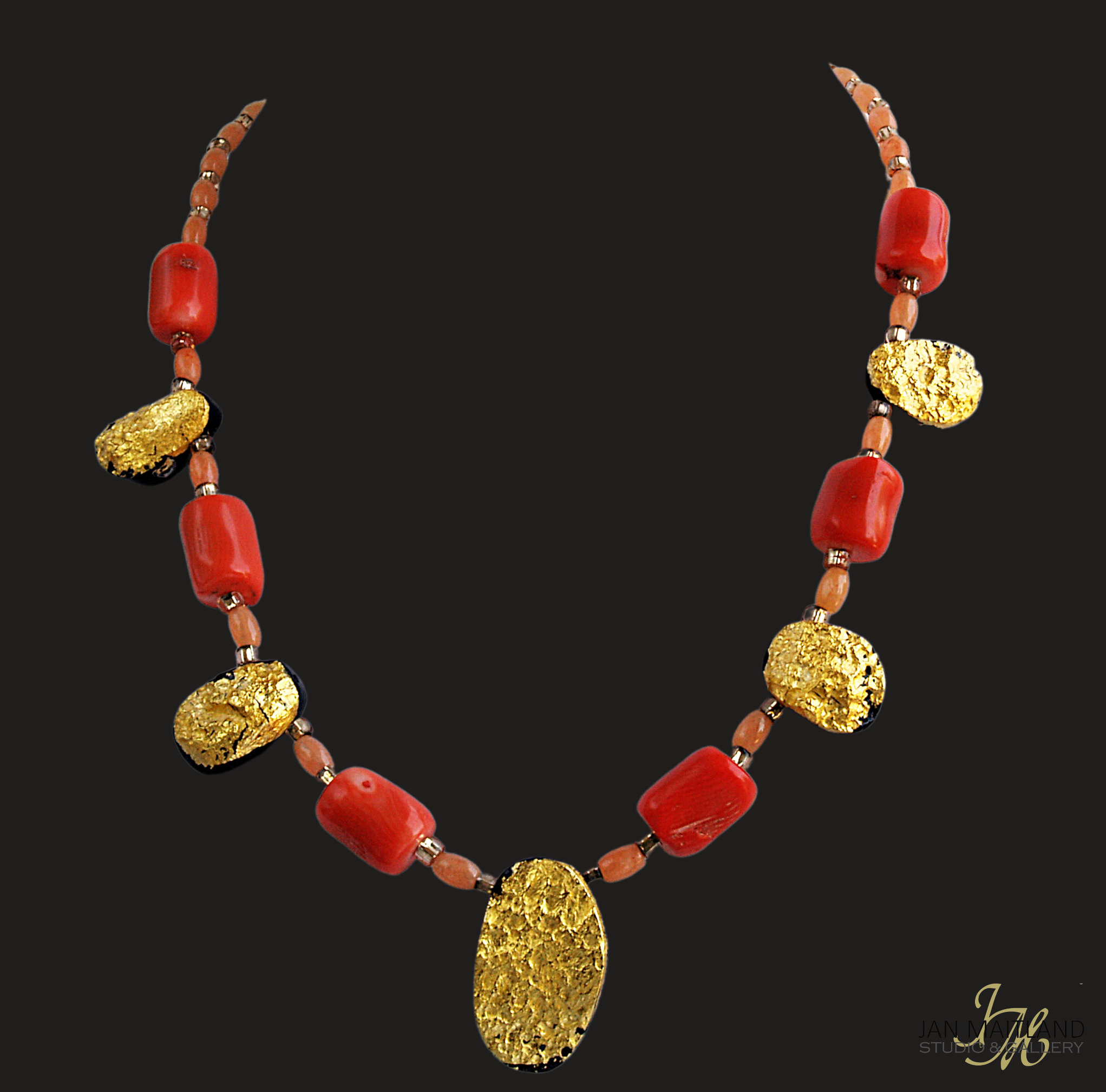 Gold and coral necklace. There are five oval, tearshaped gold gilded textured tektite stones. The center stone is larger than the others. Inbetween are dark orange barrel shaped and oval shaped coral beads with small gold glass beads inbetween.