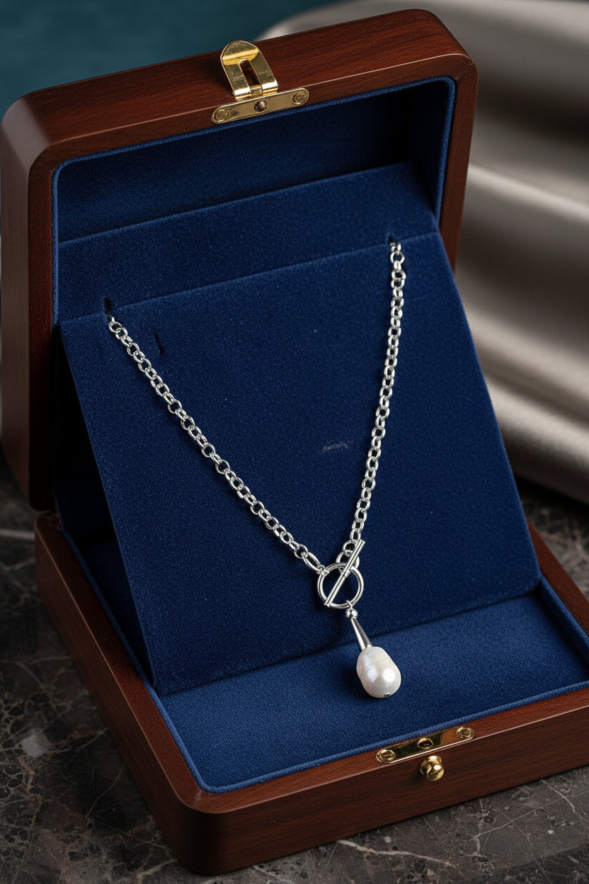 Silver necklace with a pearl pendant in a blue and wood jewelry box.