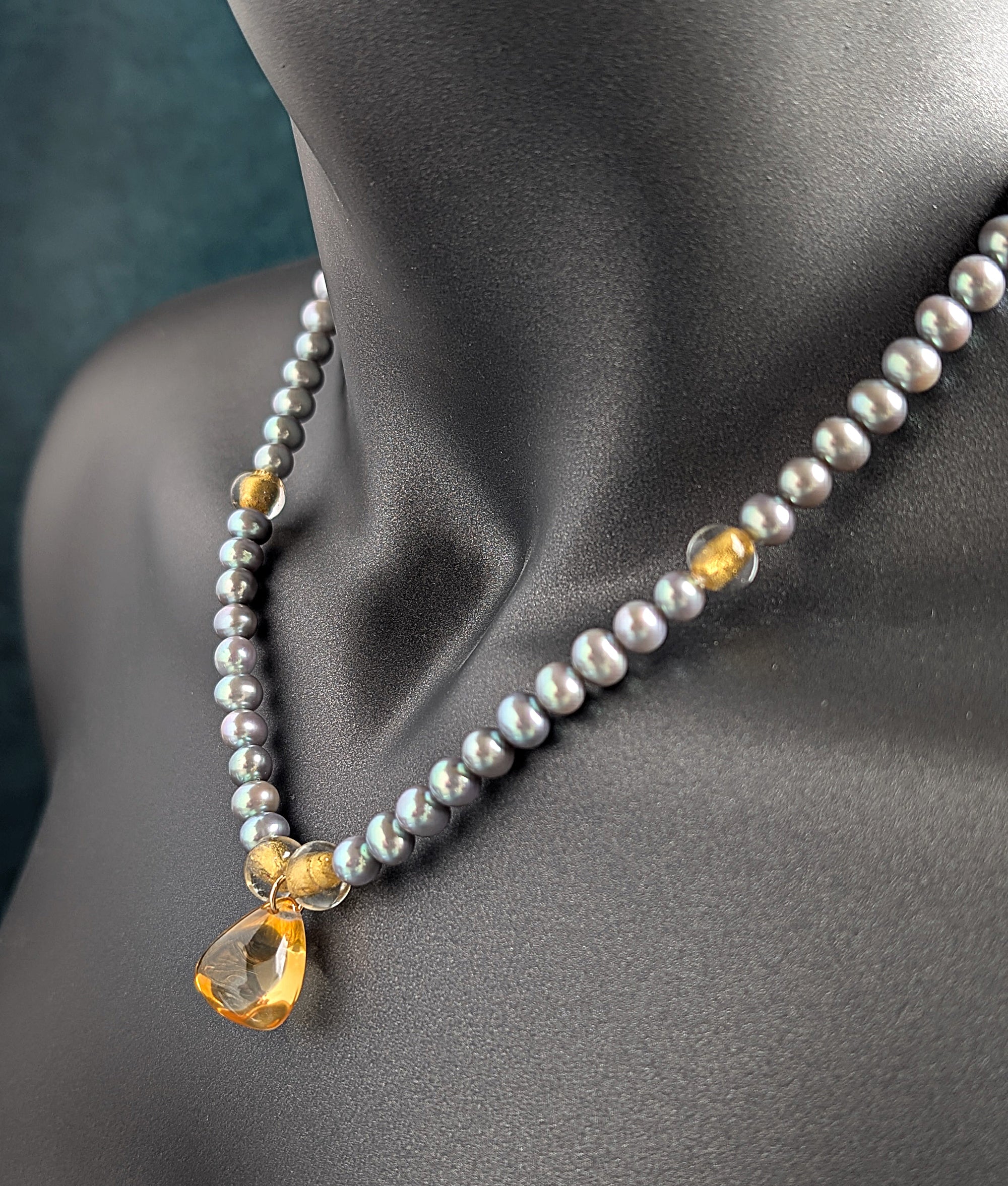 Pearl and citrine pendant necklace with gold accents on a mannequin against a dark background