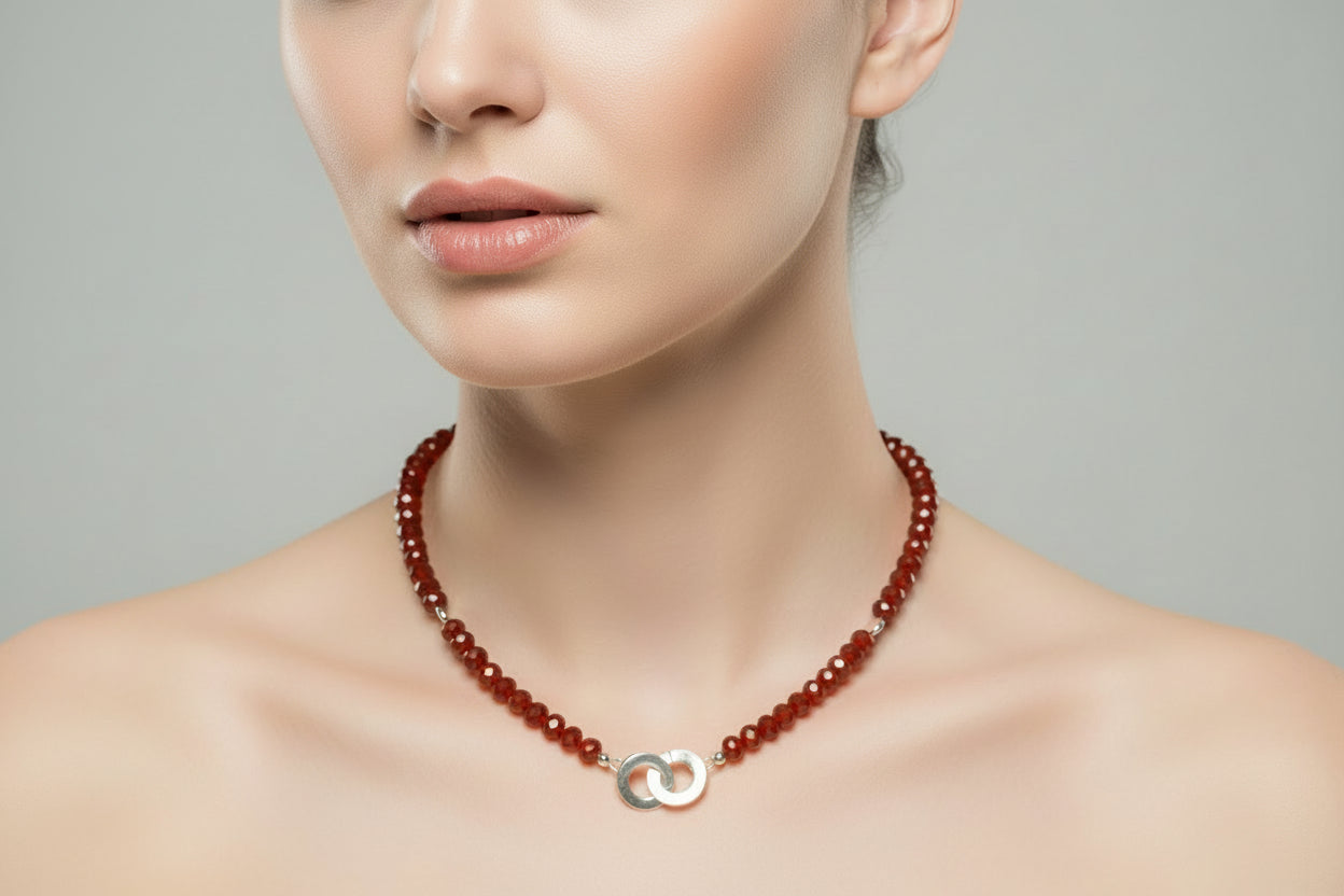 Woman wearing a red beaded necklace with a silver pendant.