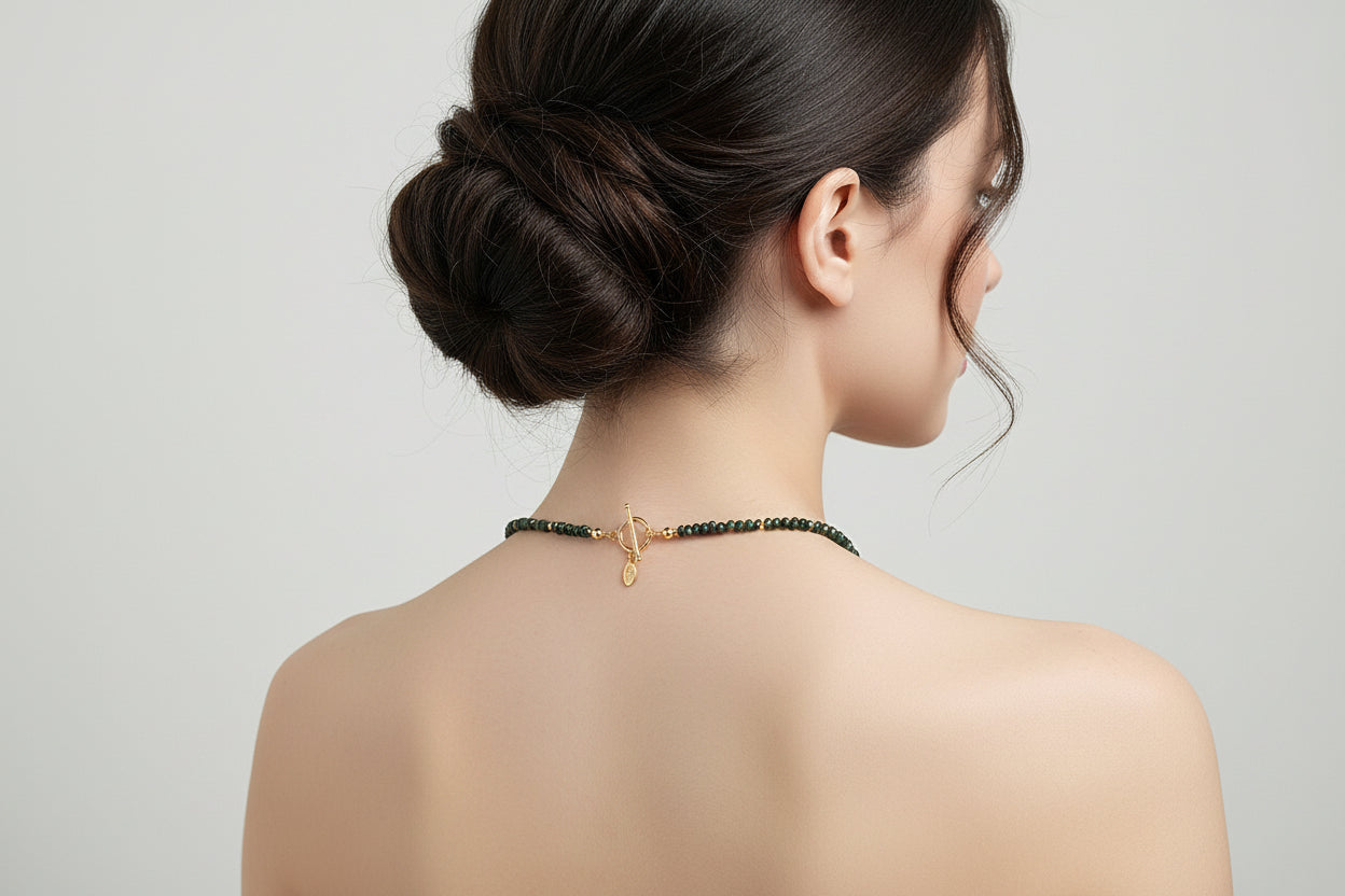 Back of green and gold necklace showing gold toggle clasp on a model. mannequin.