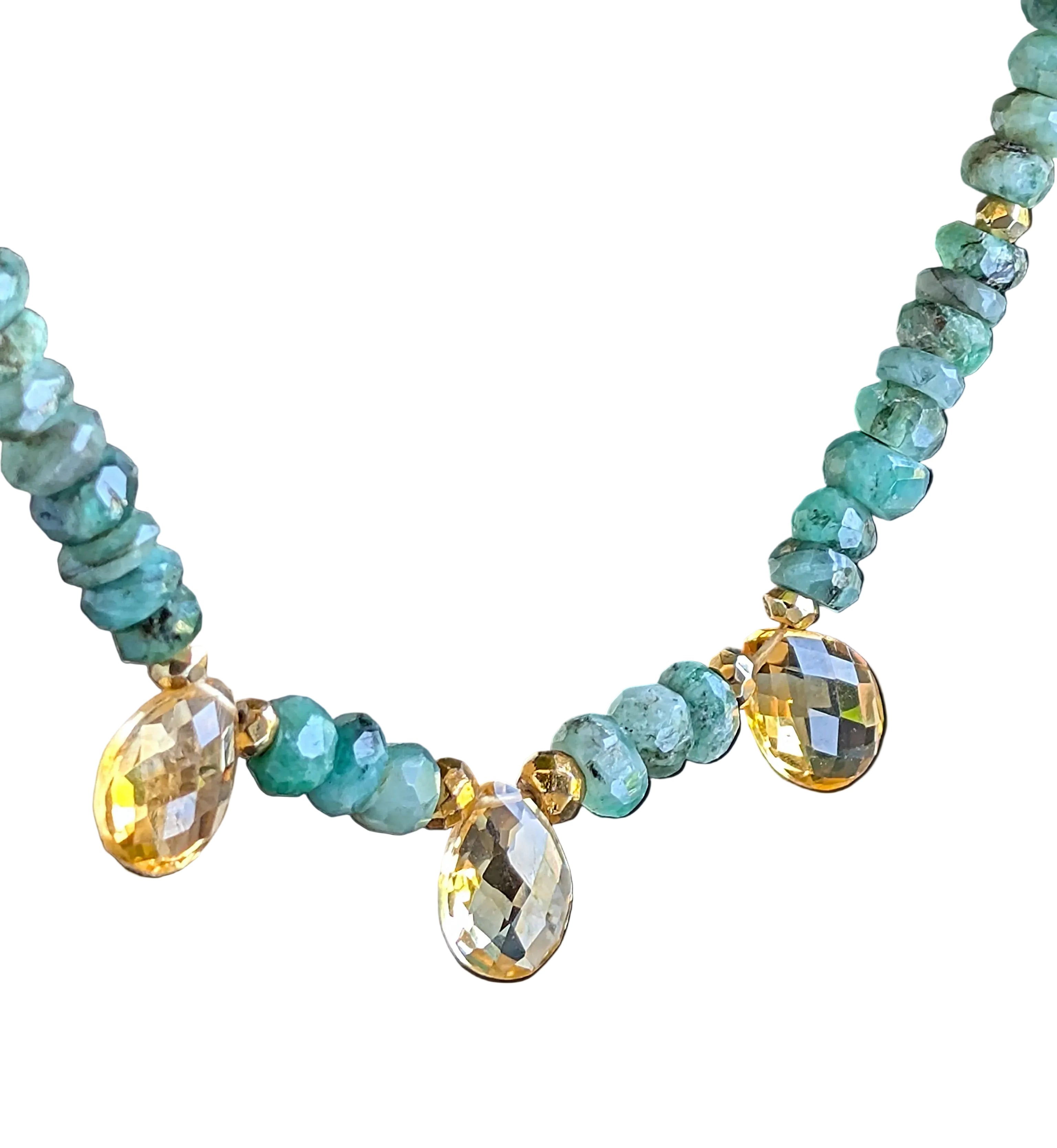 A necklace with green emerald beads and faceted citrine briolette gems on a white background.