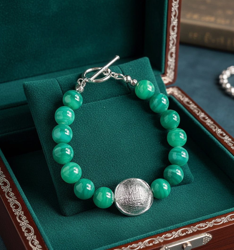 Green beaded bracelet with a silver clasp in a green velvet and wood jewelry box.