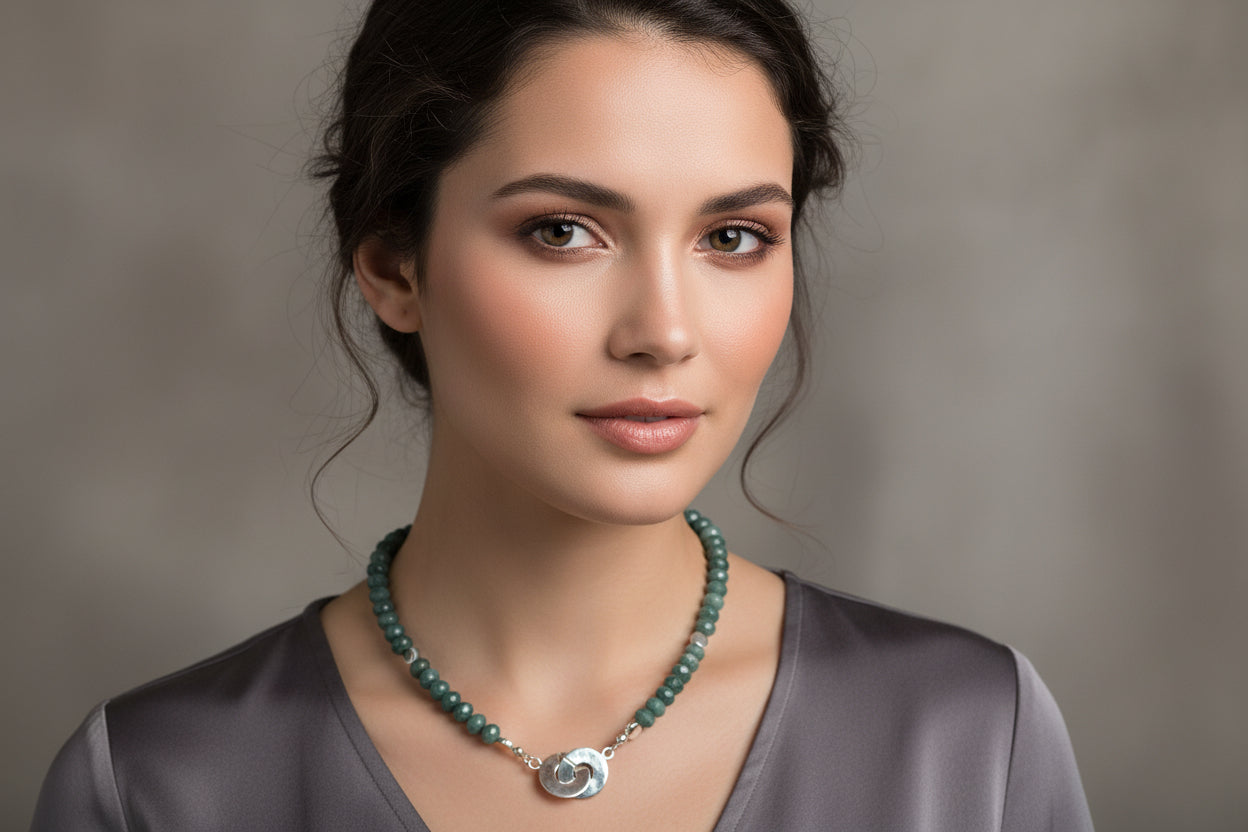 Necklace with green jade beads and a circular silver pendant on a model.