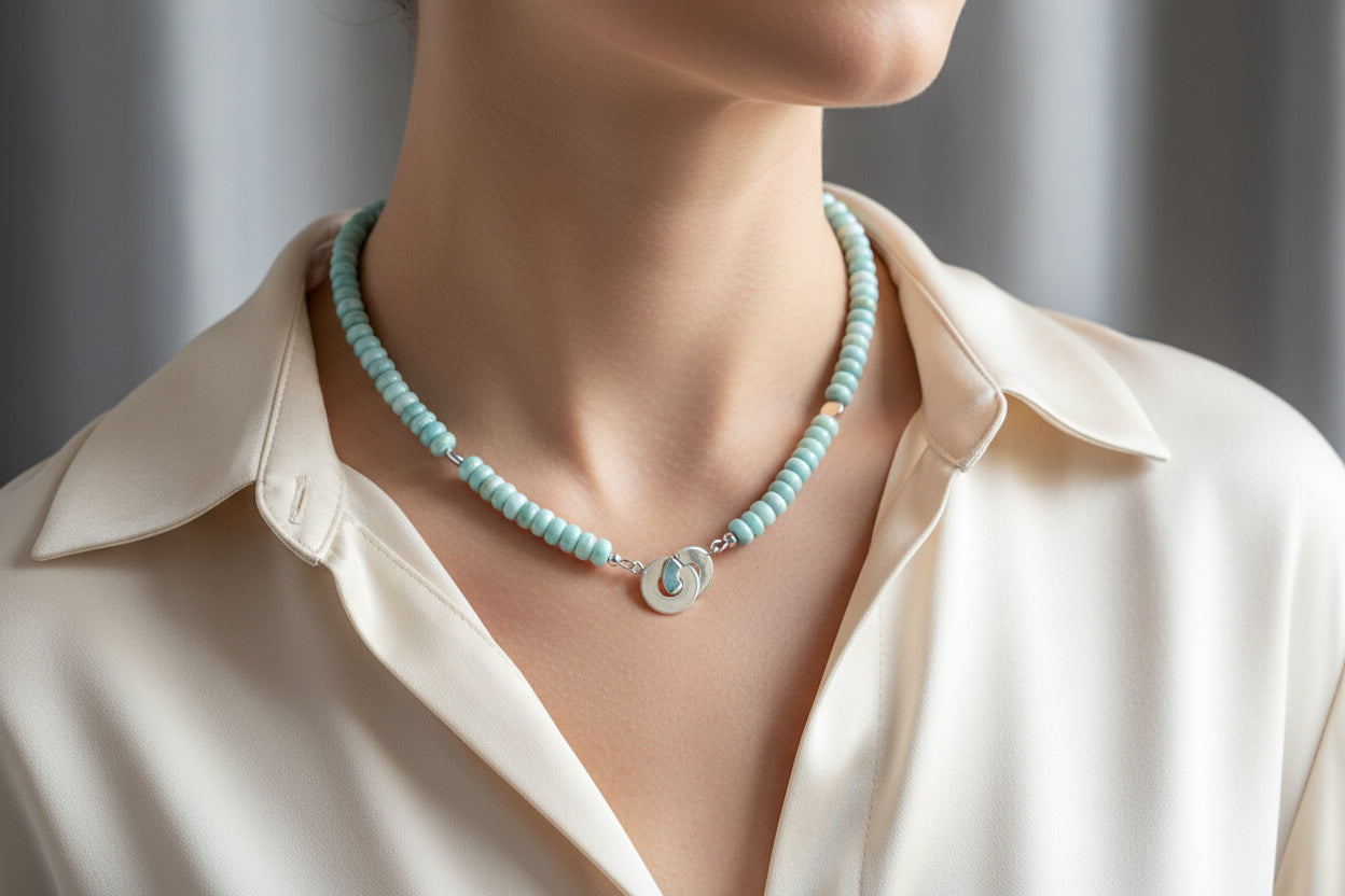 Blue larimar and sterling silver necklace on a model wearing a cream blouse