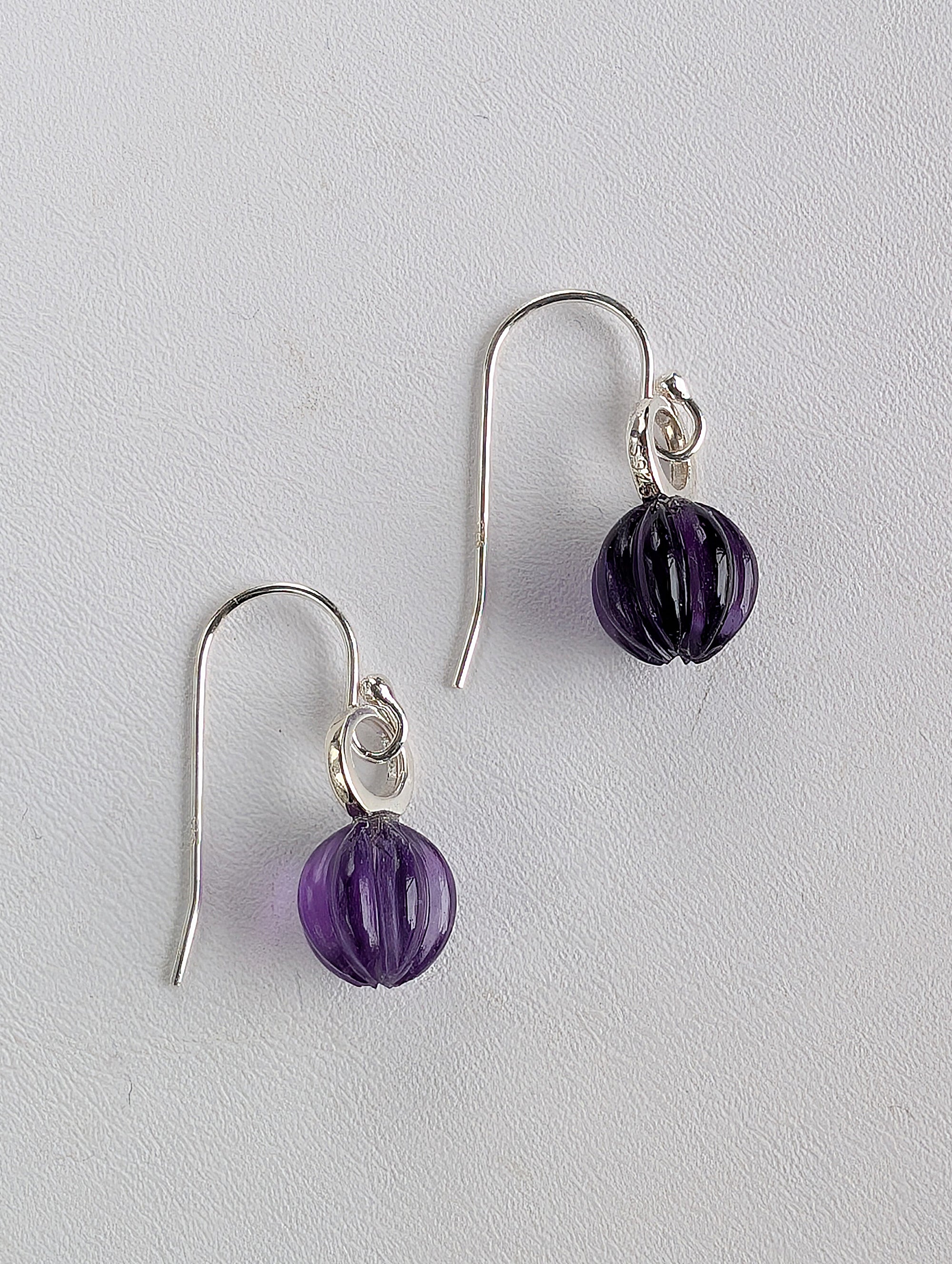 Pair of purple beaded earrings on a light gray background