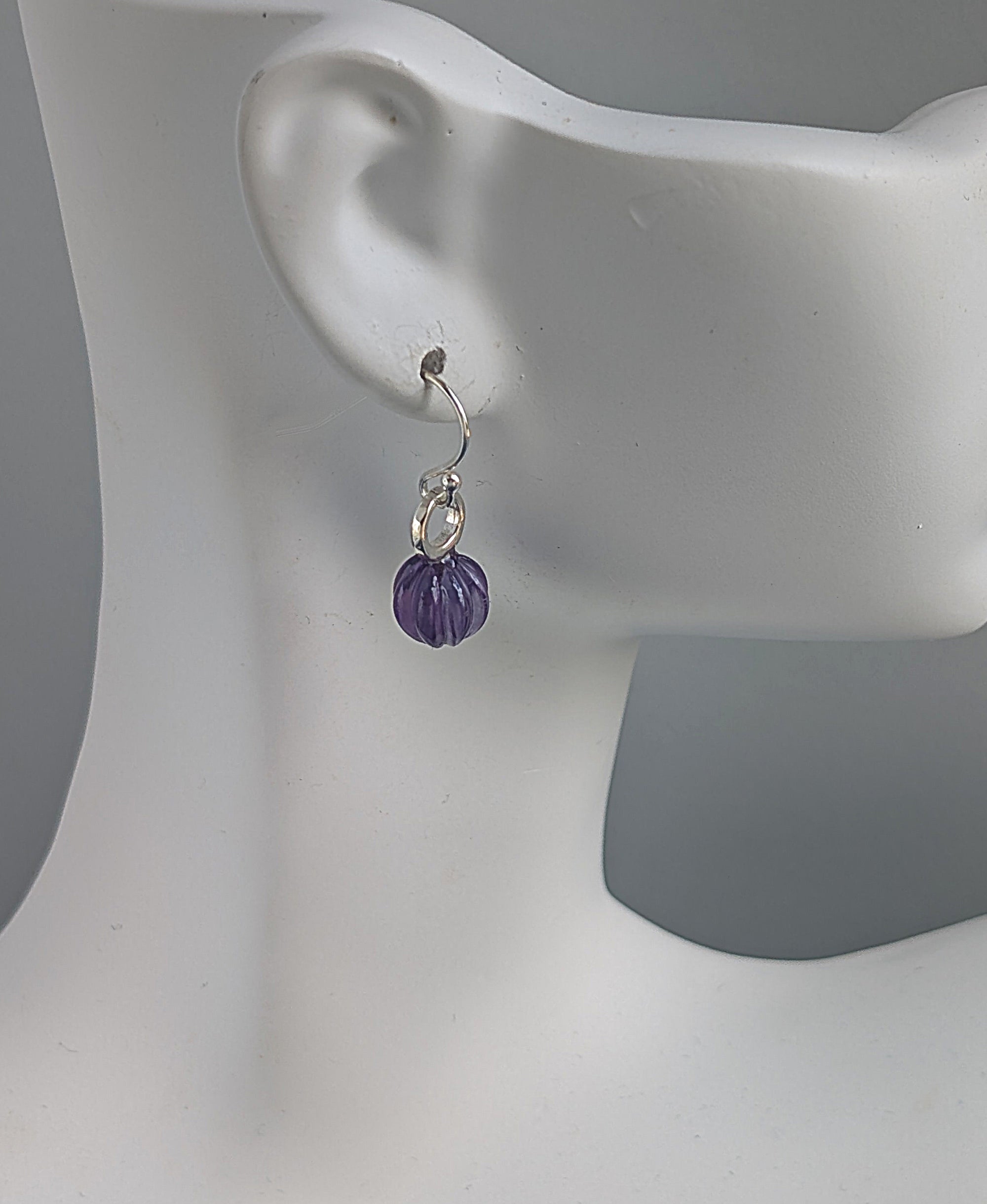 Purple beaded earring on a mannequin ear