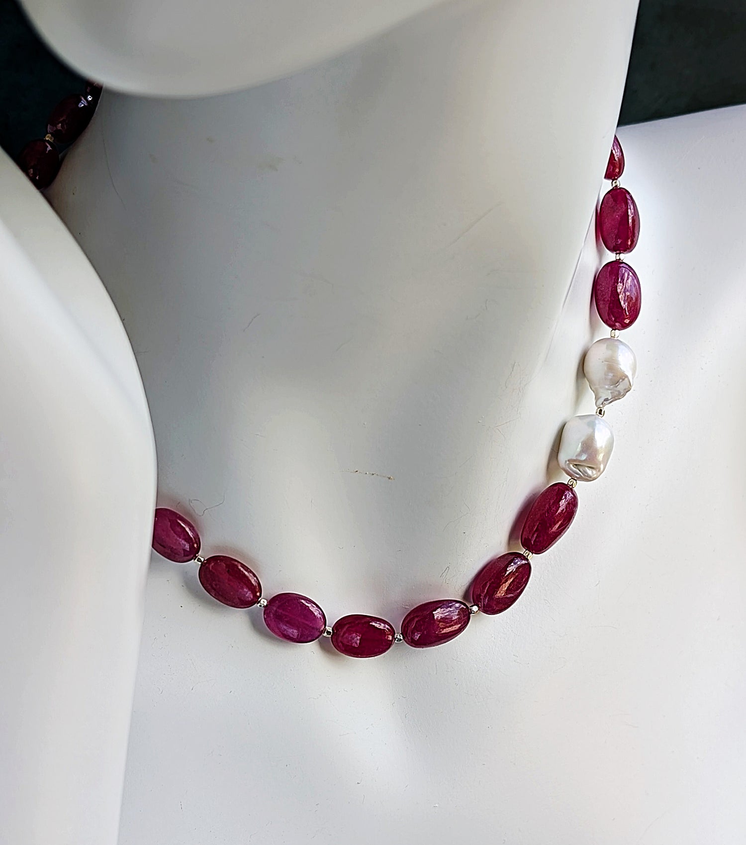 Cabochon rubies with two brooch like baroque pearls on a mannequin neck.