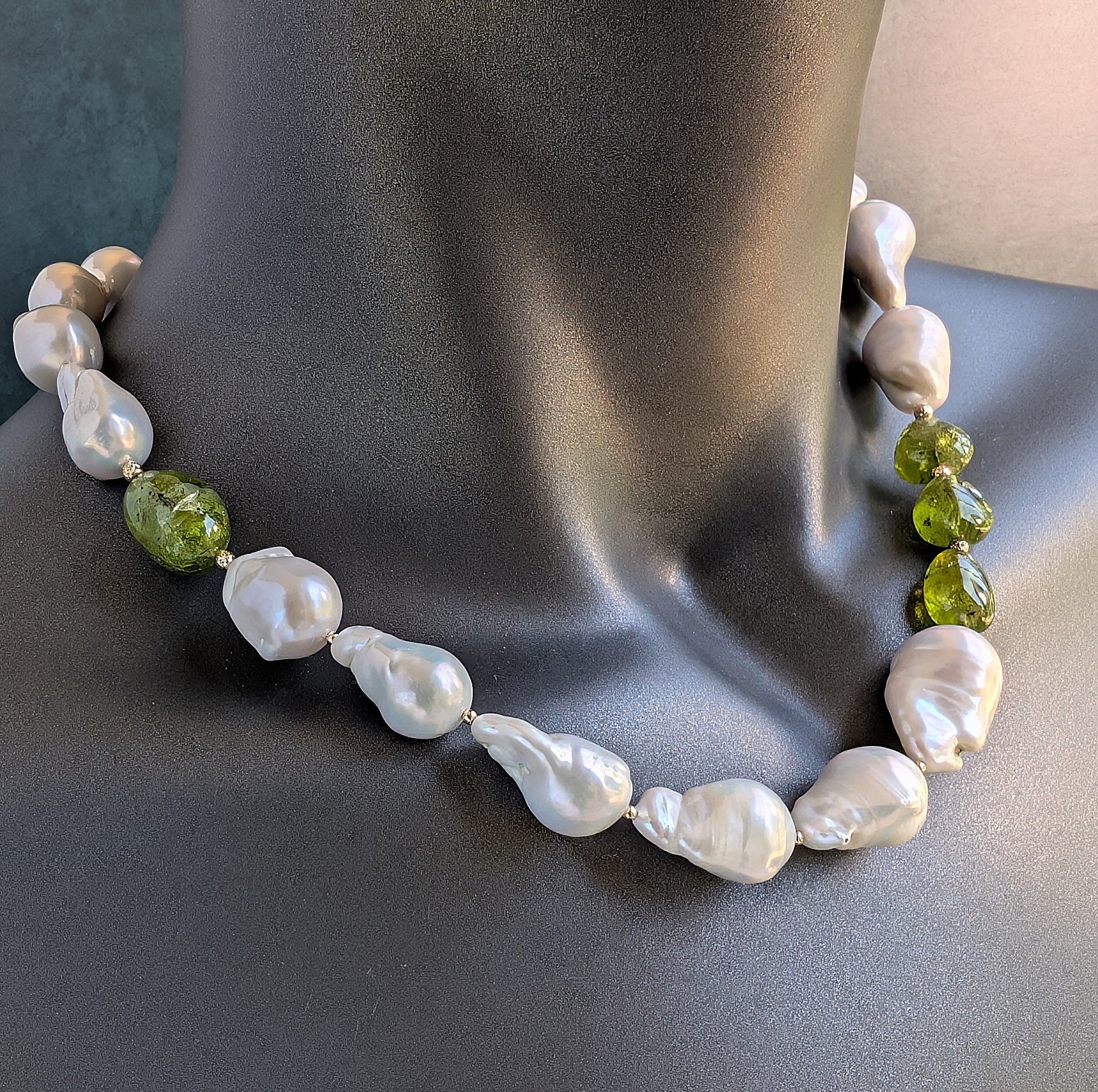 Necklace with white pearls and green beads on a dark surface