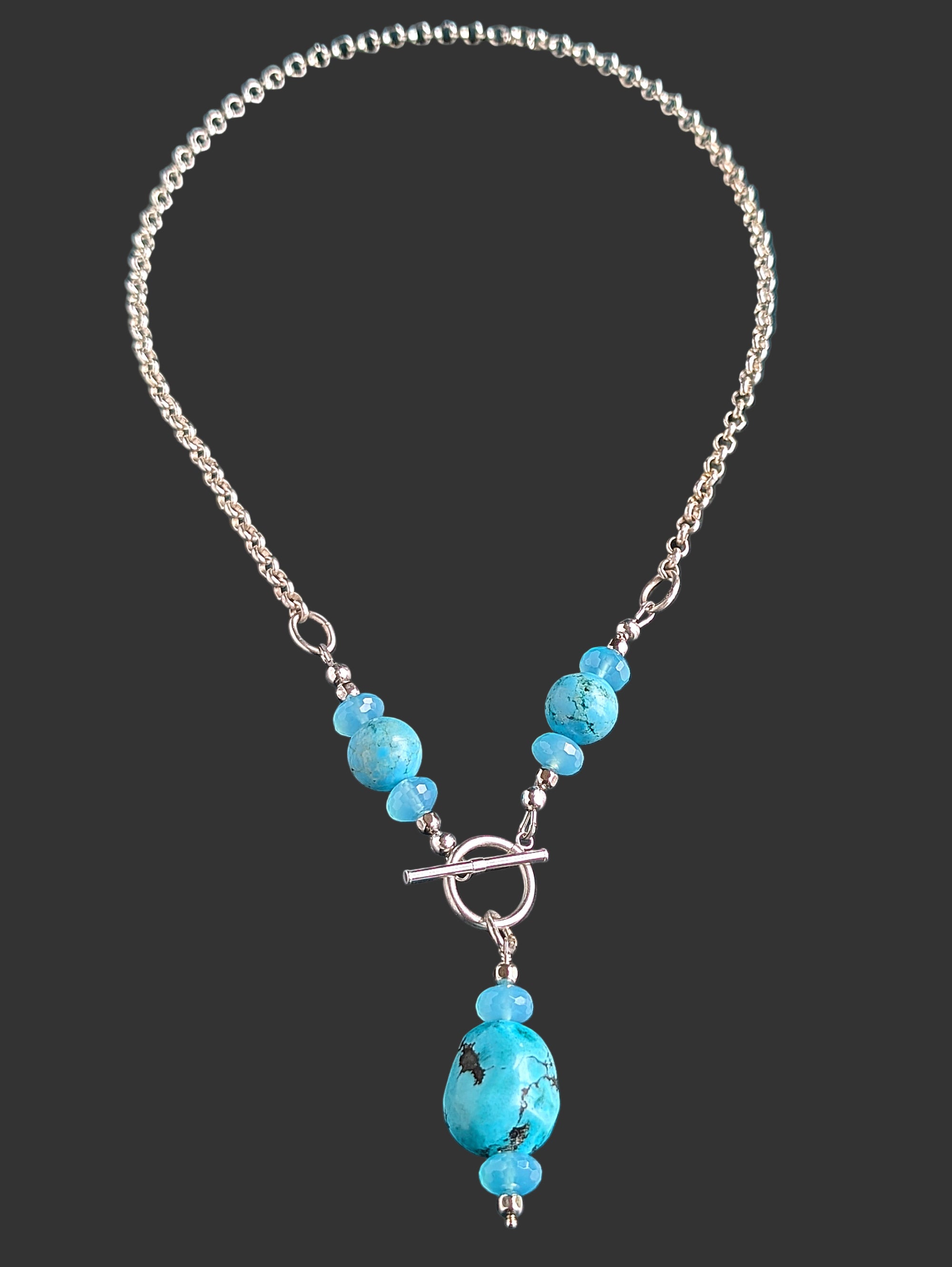 Turquoise and silver toggle necklace on a black background.