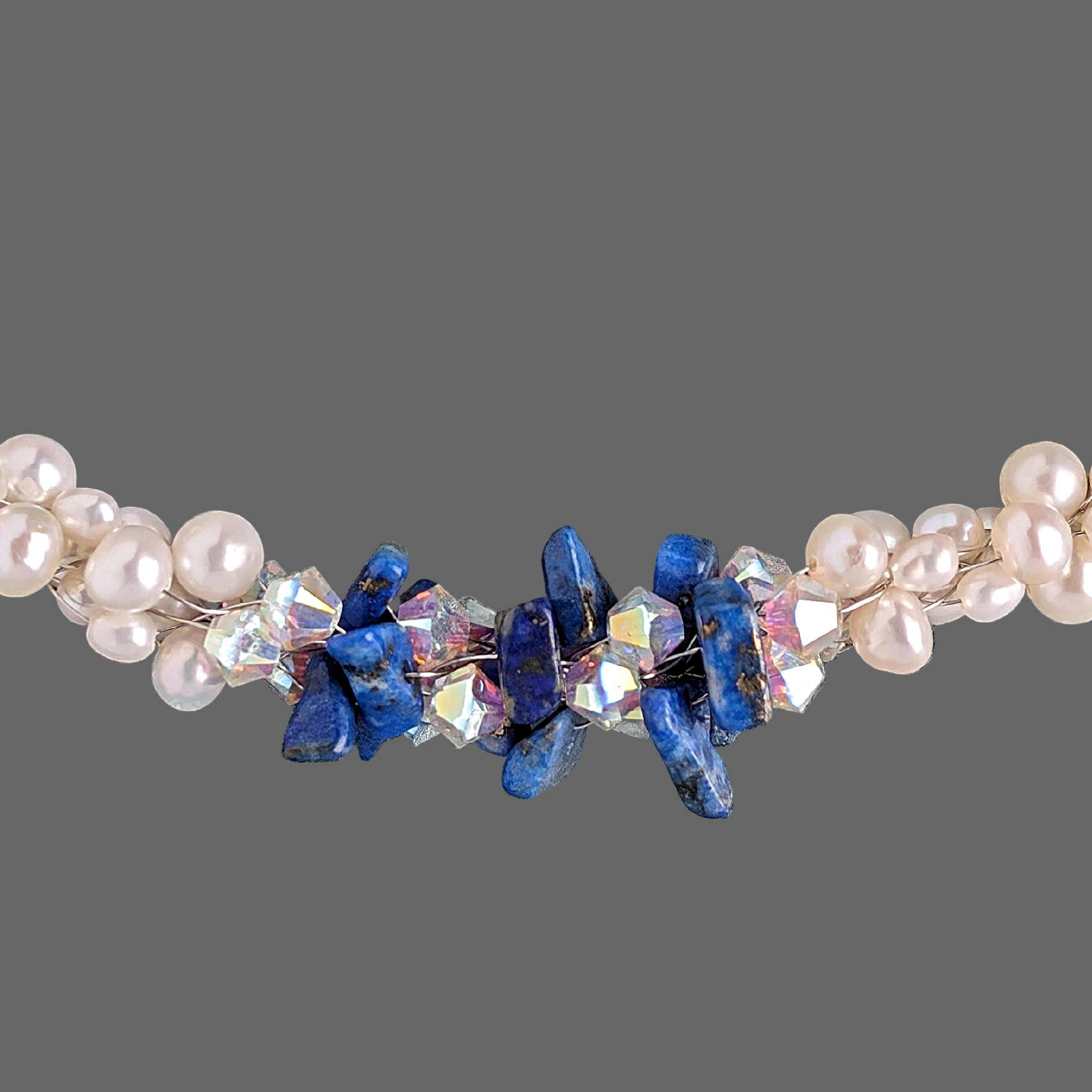 Necklace with pearls, blue stones, and clear crystals on a textured gray background