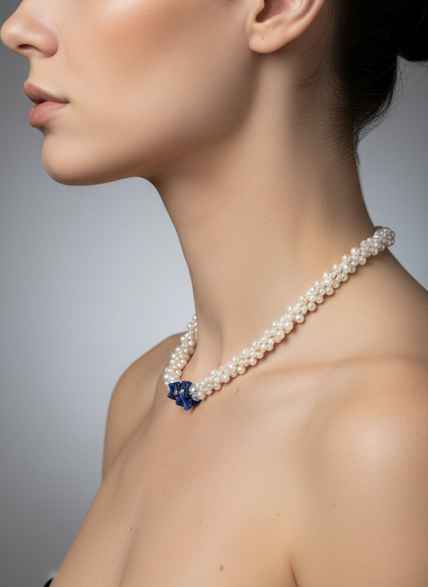 Pearl necklace with a blue lapis worn by a model on a gray background