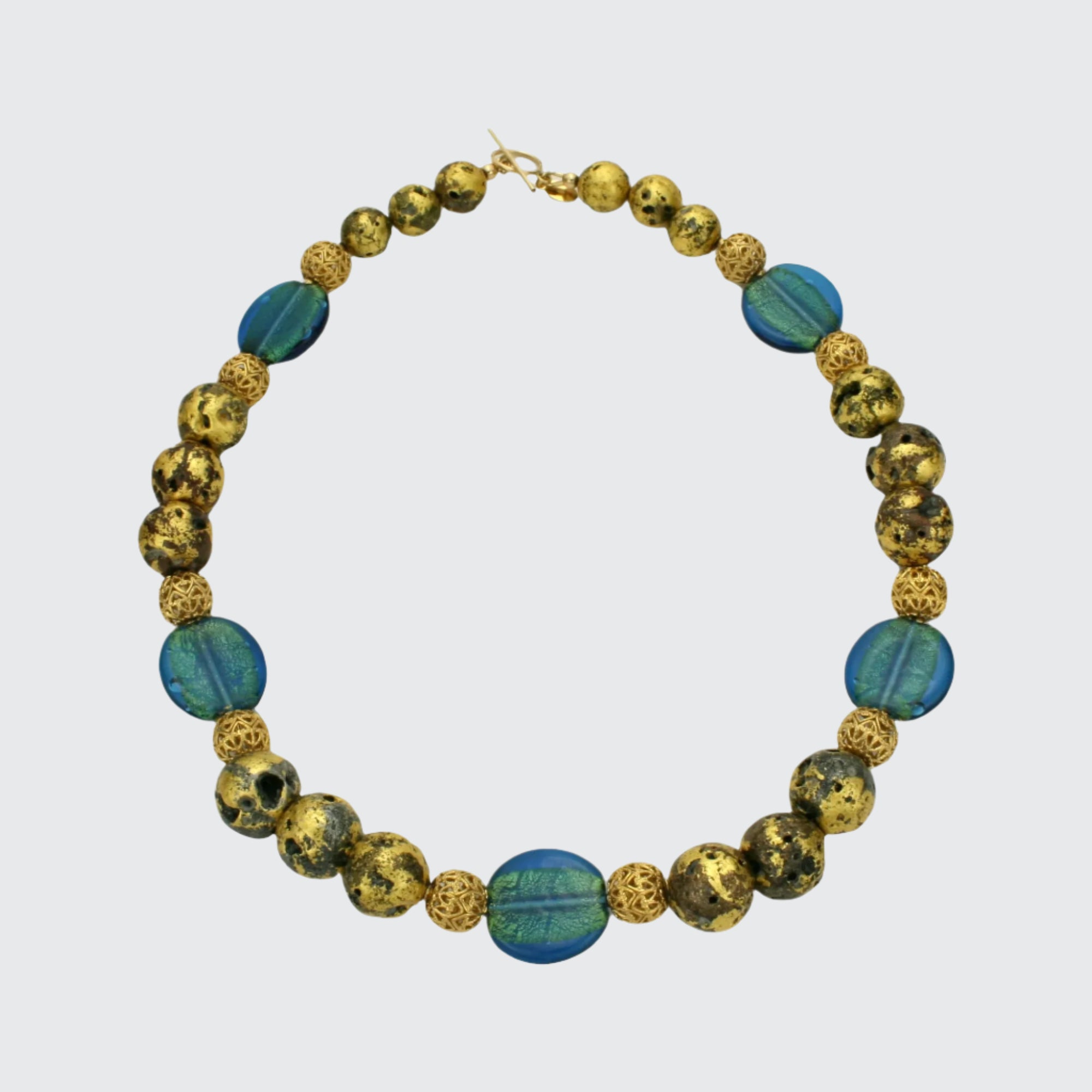 A necklace with blue lampwork Czech glass beads, gold mesh beads, and 23-Karat gold leaf on lava stone, finished with a 14-Karat gold-filled toggle clasp.