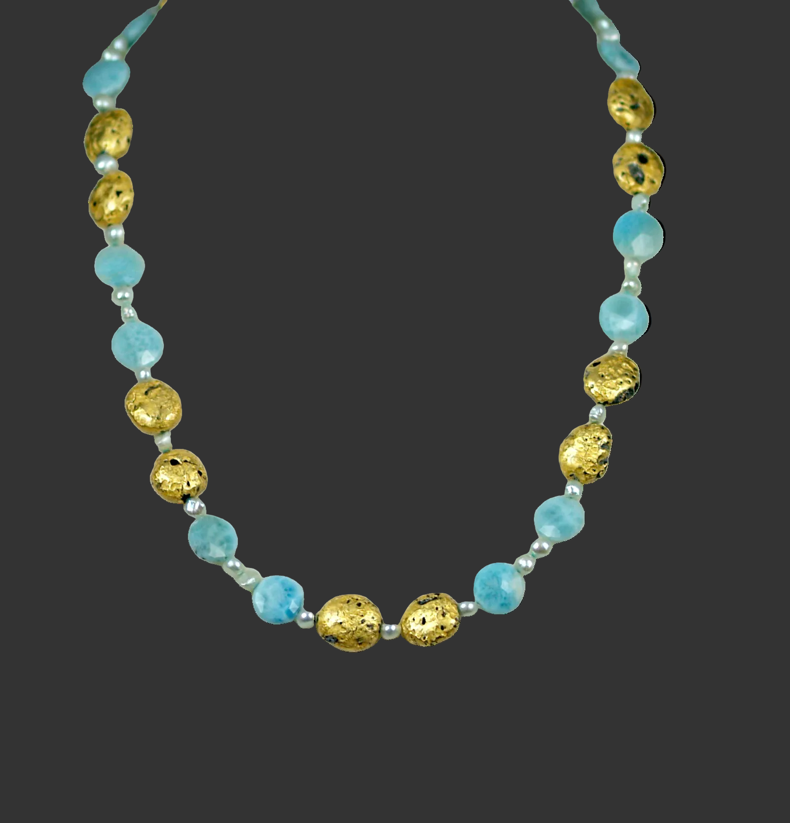 Blue larimar and gold gilded necklace on dark gray background.
