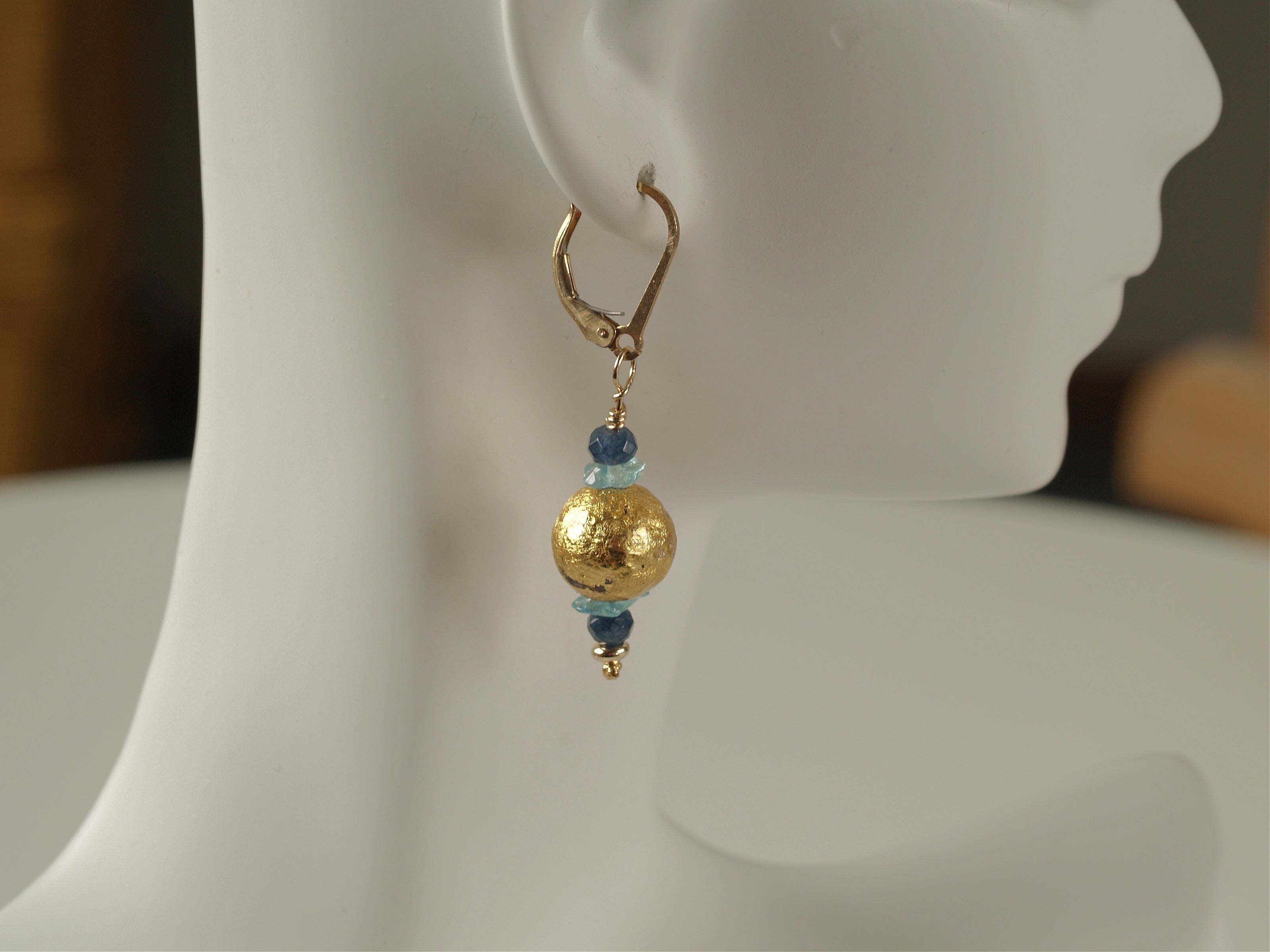 4mm faceted dark blue onyx, aqua apatite, and 23 karat gold gilded round lava stone with 14-karat gf leverback earrings on a small mannequin.