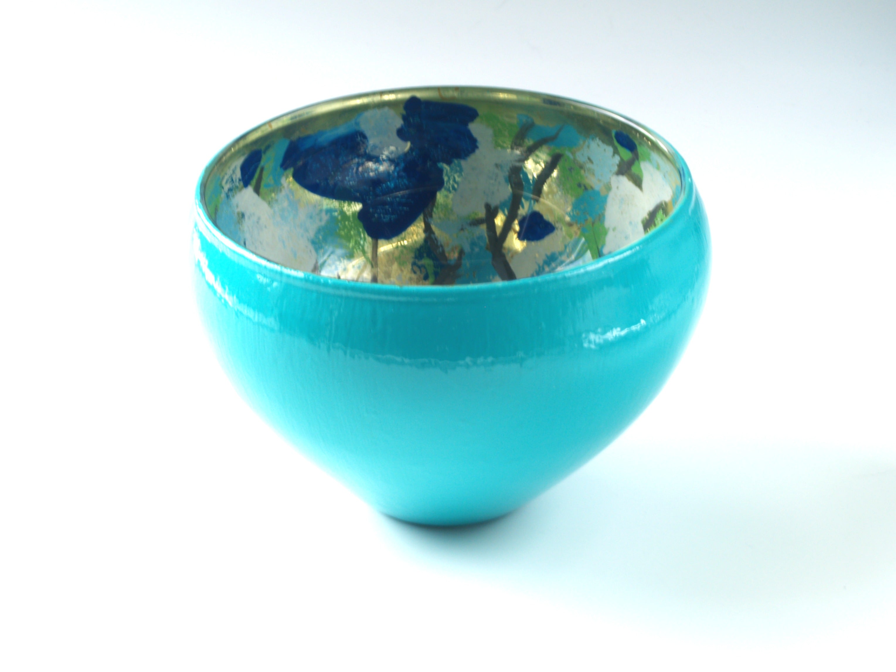 Turquoise, blue, and gold glass bowl on white background.