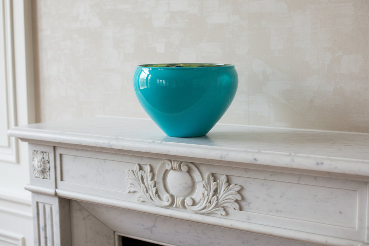 Turquoise glass bowl on a white mantle as background.