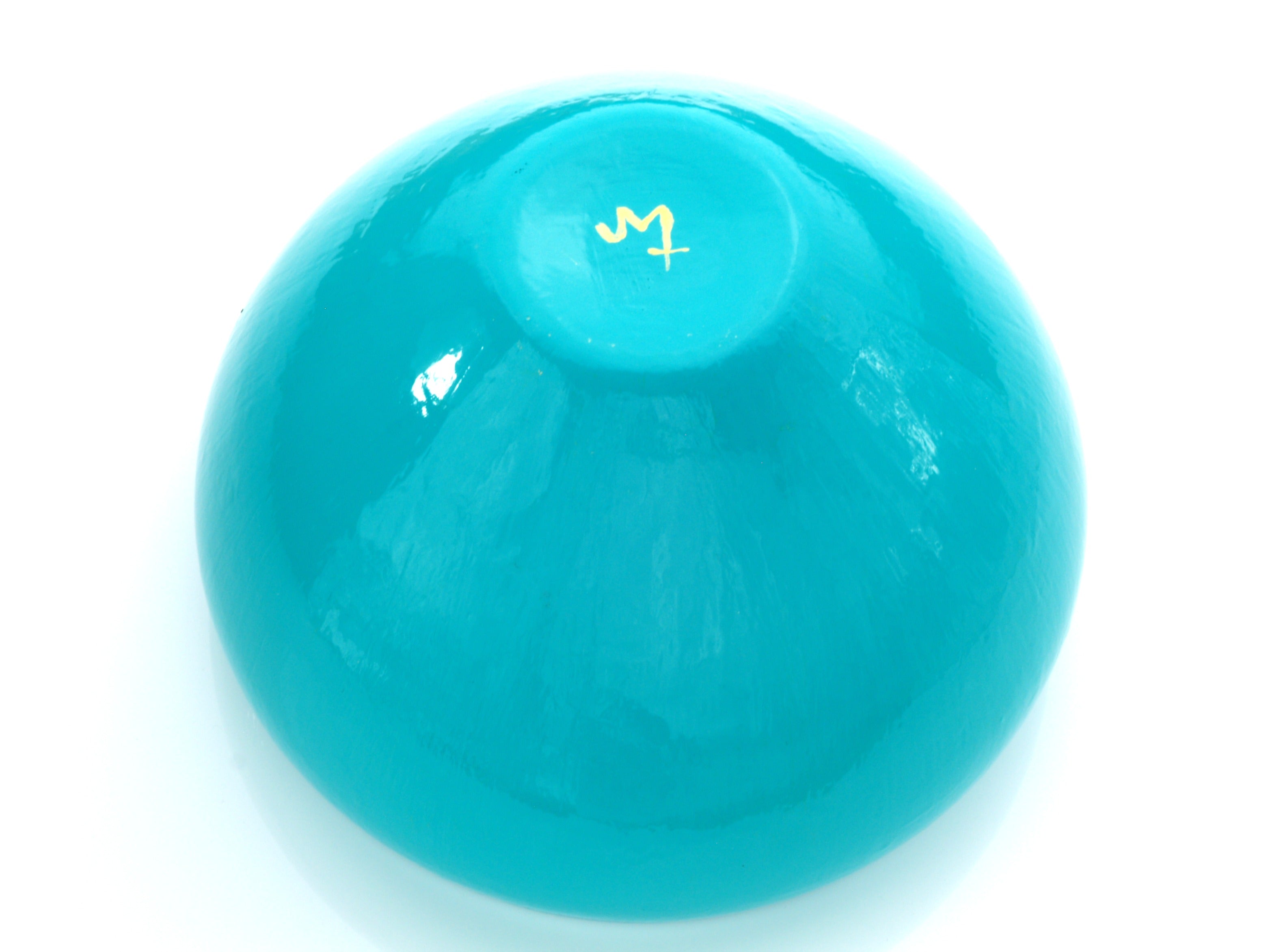 The bottom of turquoise bowl showing signature on a white background