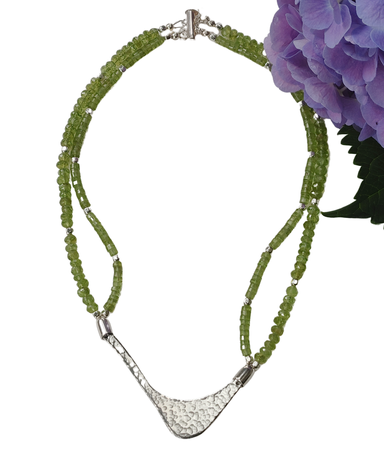 Hammered silver abstract pendant necklace with two strands of peridot and silver beads. The necklace is finished with a magnetic clasp and the artist&