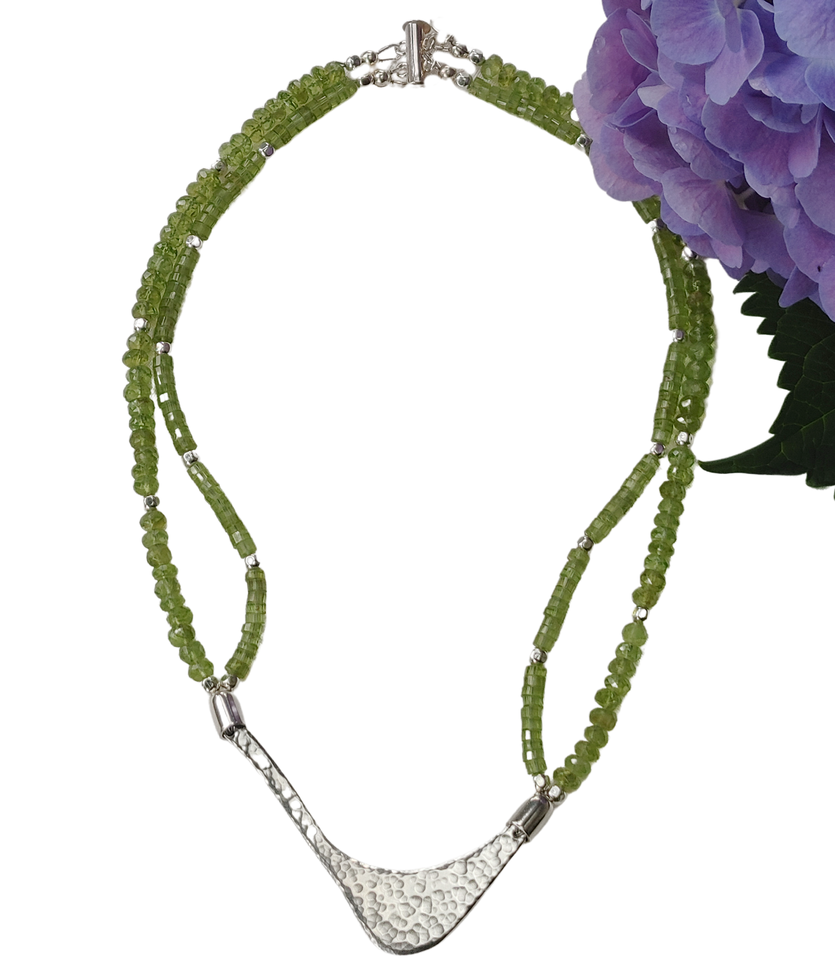 Hammered silver abstract pendant necklace with two strands of peridot and silver beads. The necklace is finished with a magnetic clasp and the artist&