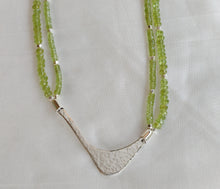 Load image into Gallery viewer, Hammered silver abstract pendant necklace with two strands of faceted peridot and silver beads. The necklace is displayed on a white background.