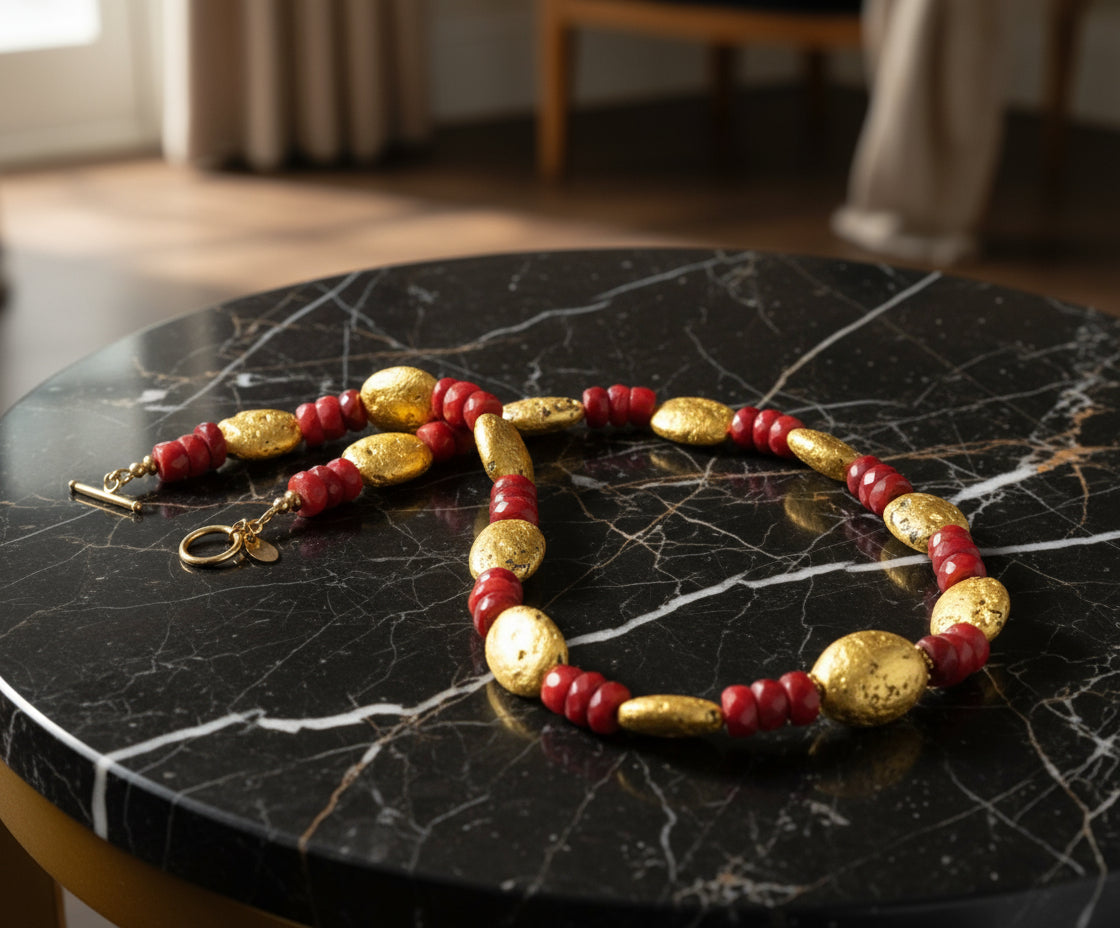 Necklace with red and gold beads on a black marble surface