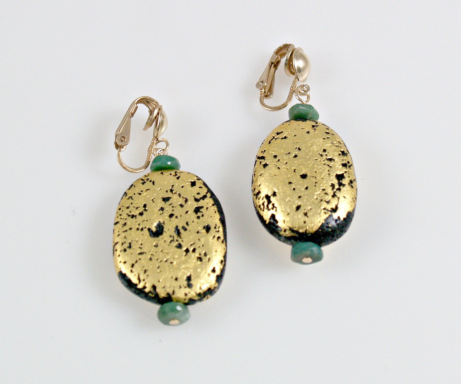 A pair of clip earrings featuring a gilded gold lava stone with green chrysoprase accents.