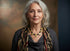 Woman wearing a patterned scarf and gold necklace against a blurred background