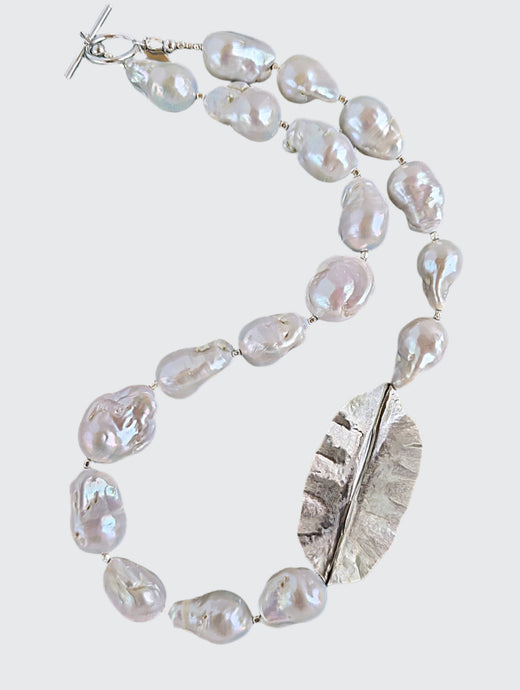 White Baroque pearl and silver necklace with hammered and fold form leaf design in silver with small silver beads in between each pearl. Necklace is finished with silver toggle clasp and designer tag.