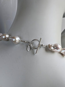 Back of White Baroque pearl necklace showing sterling silver toggle clasp and designer signature tag.