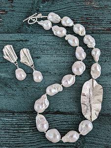 Shown together are White Baroque pearl and silver necklace and earrings with hammered and fold form leaf design in silver with small silver beads in between each pearl. Necklace is finished with silver toggle clasp and designer tag.