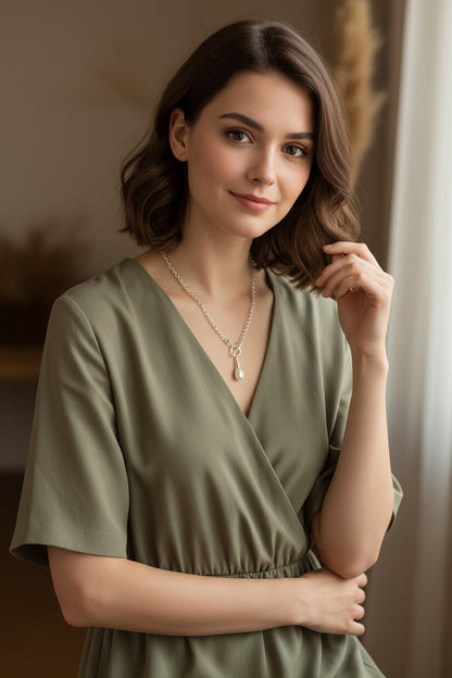 Silver necklace with a pearl pendant on a model.