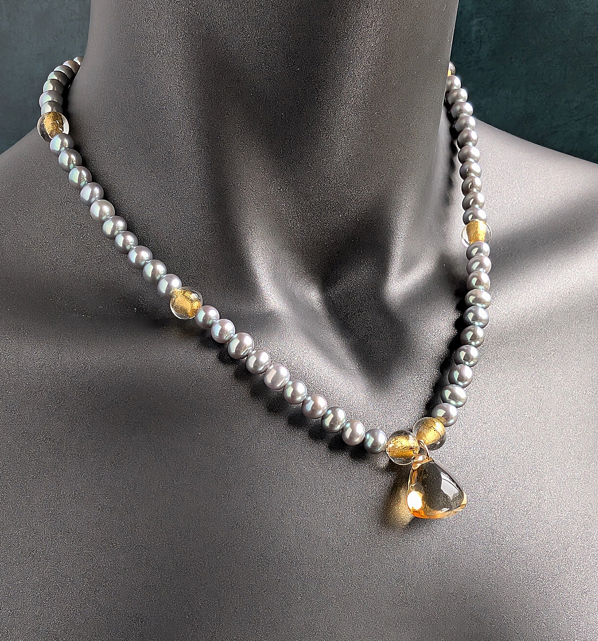 Necklace with gray pearls and a teardrop-shaped citrine pendant on a mannequin.