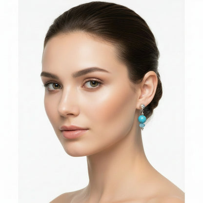 Turquoise bead earring with silver accents on a model.