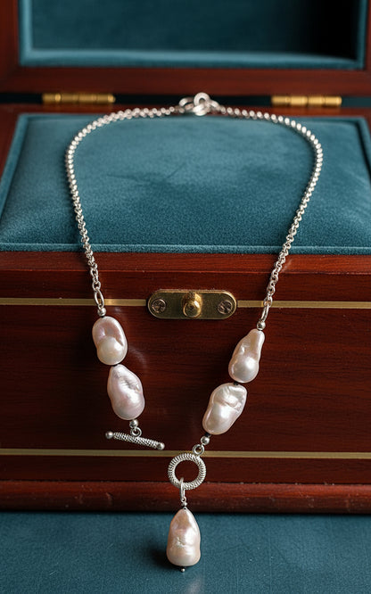 Necklace with white pearls and silver chain in a teal and wood jewelry chest.