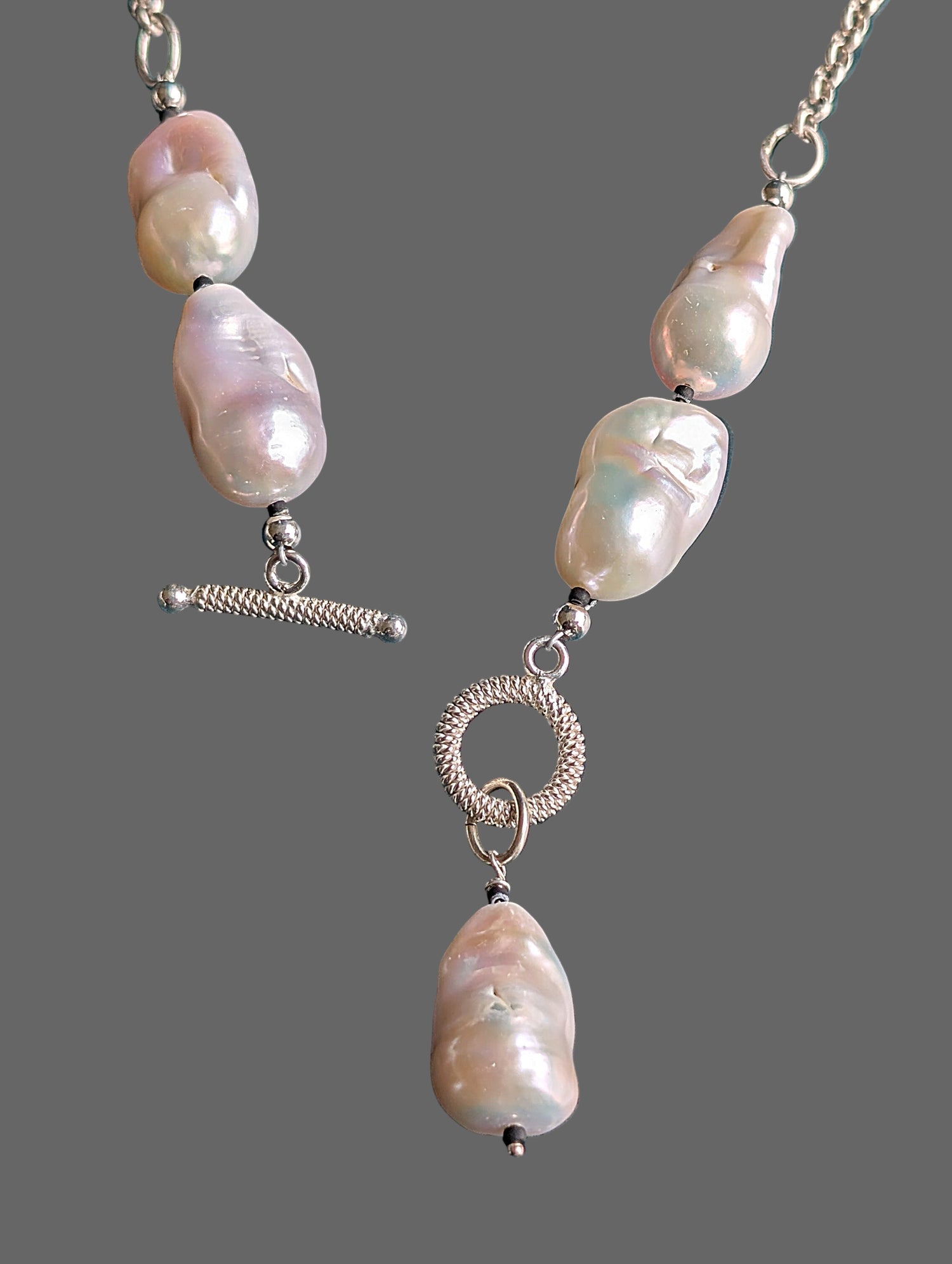 Pearl necklace with silver clasp on a grey background