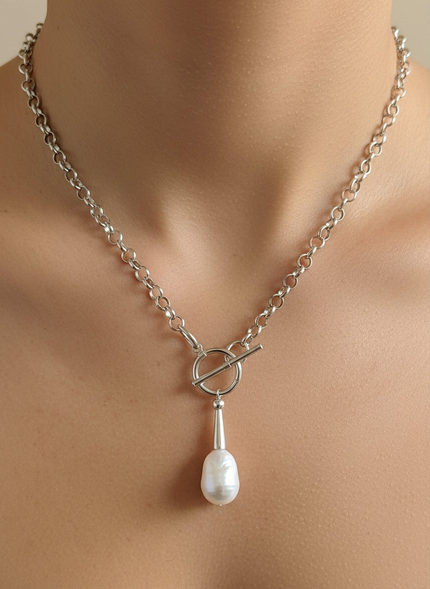 Silver necklace with a toggle clasp and pearl pendant on a model.