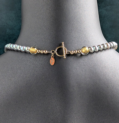 The back of Pearl and gold necklace showing the gold toggle clasp on a mannequin with a dark background