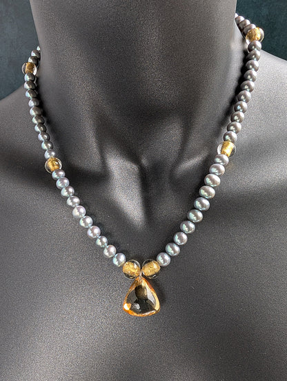 Necklace with gray pearls, citrine pendant and gold accents on a mannequin
