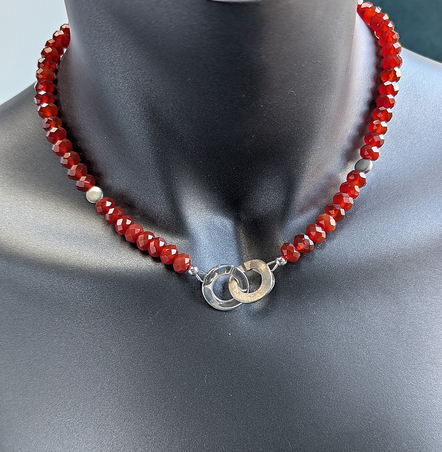 Red beaded necklace with silver clasp on a mannequin