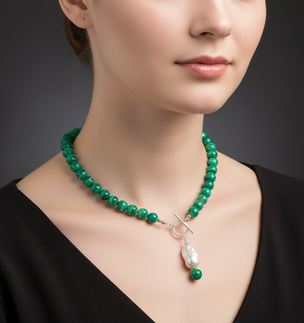 Green beaded necklace with a pearl pendant on a model.