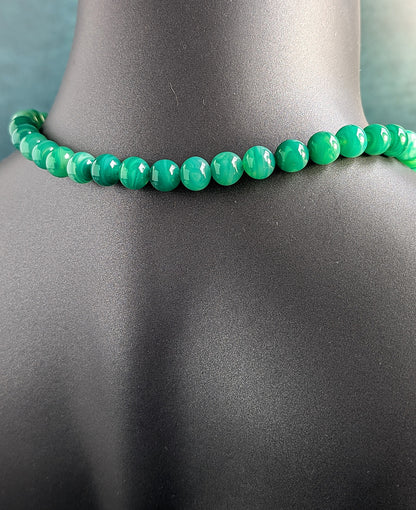 The back of green beaded necklace on a mannequin with a gray background