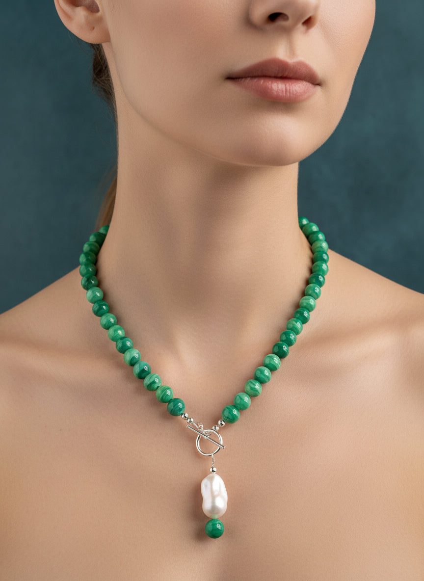 Green beaded necklace with a pearl pendant on a model.