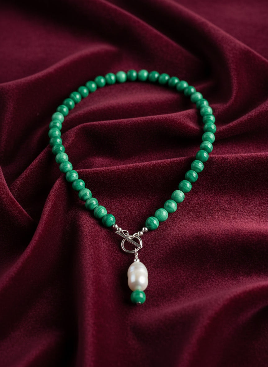 Green beaded necklace with a pendant on a dark red background